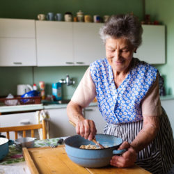 Senior woman baking pies in her home kitchen.  Mixing ingredients.